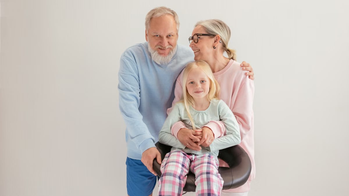 Smiling grandparents with grandchild, embracing intergenerational love.
